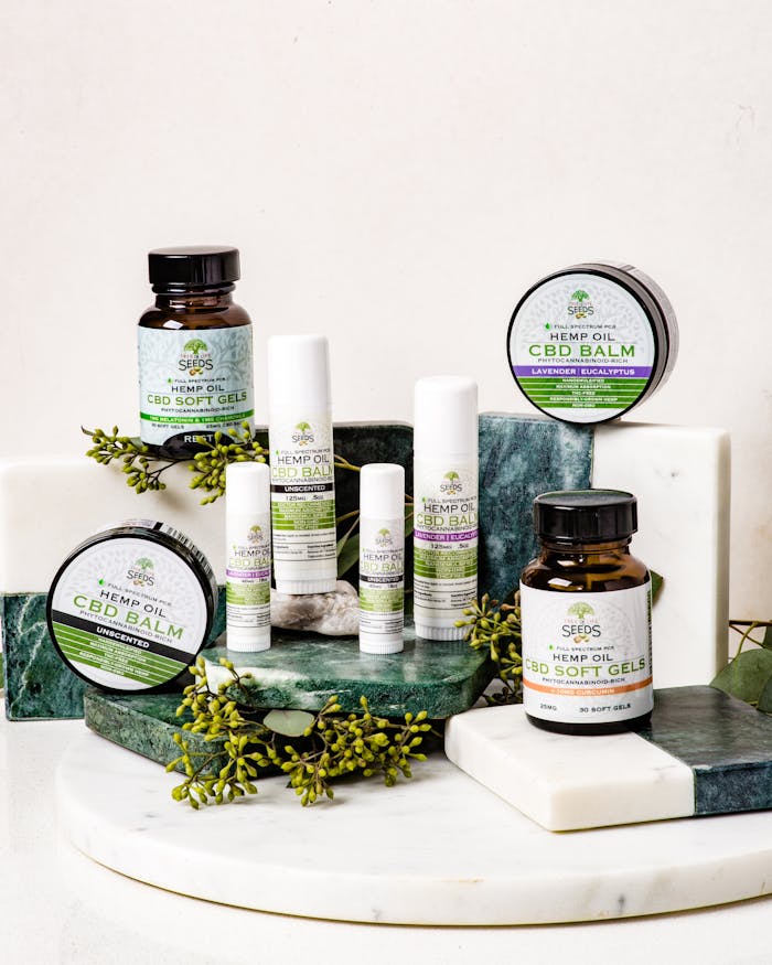 services-03 An assortment of CBD products including balms and softgels arranged on a marble stand.