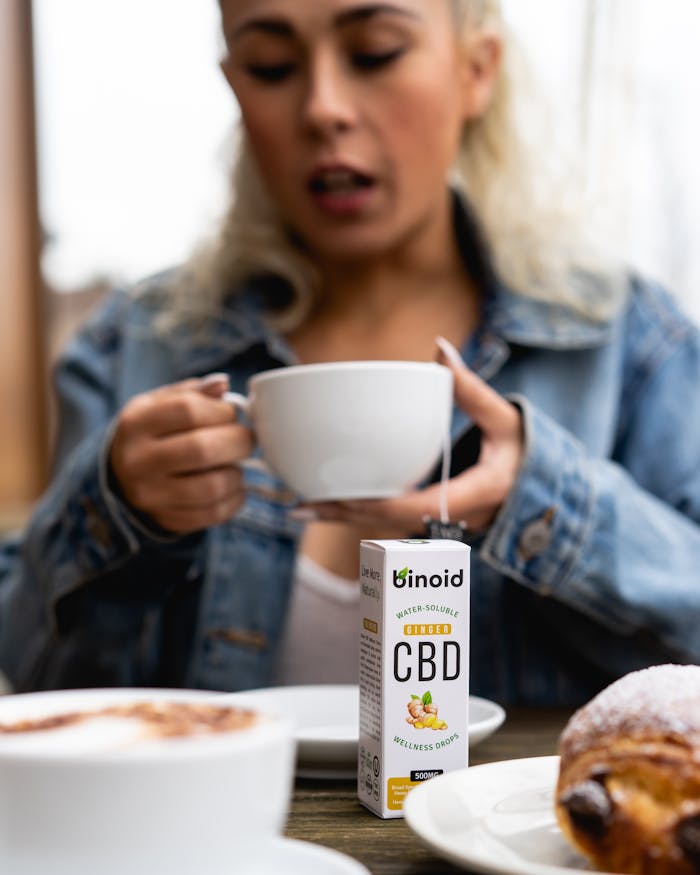 who-we-are A woman savoring a CBD-infused coffee alongside a pastry, promoting wellness lifestyle.