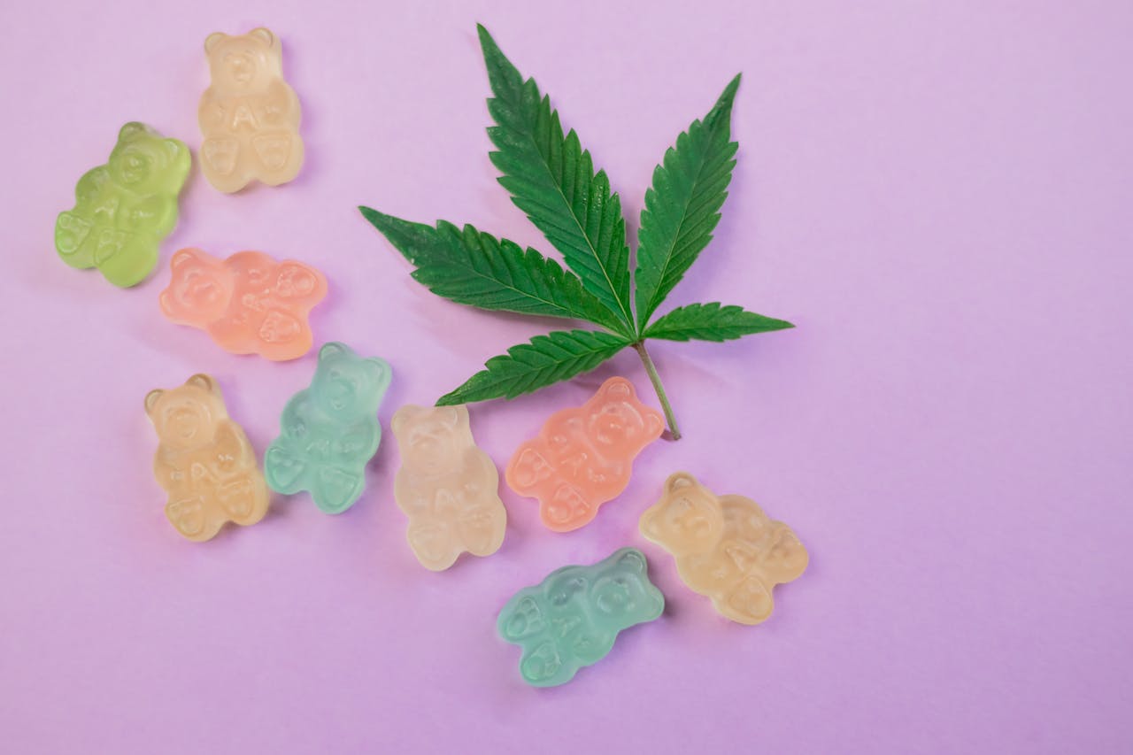 about-us Vibrant gummy bears and a cannabis leaf on a pastel background, symbolizing cannabis edibles.